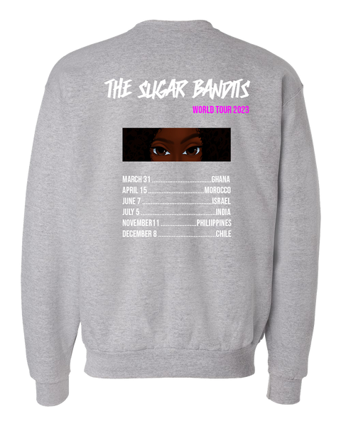 The back of a heather gray crewneck sweater has The Sugar Bandits written horizontally in white at the top and World Tour 2023 written in hot pink centered under the word Bandit. There is an image of just The Sugar Bandits Bandit’s eyes centered underneath and below that are the tour dates and places they’ll visit on the tour. 