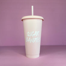 Load image into Gallery viewer, A rose blush plastic cup with a lid and straw that looks like a fast food cup is on a baby pink background. It has the The Sugar Bandits logo in white written in the center of the cup.
