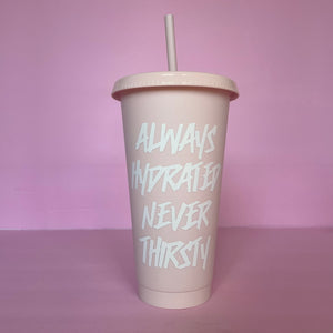 A rose blush plastic cup with a lid and straw that looks like a fast food cup is on a baby pink background. It has “always hydrated never thirsty” in white writing centered down the cup.