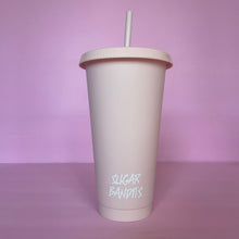 Load image into Gallery viewer, A rose blush plastic cup with a lid and straw that looks like a fast food cup is on a baby pink background. It has the The Sugar Bandits logo written in white at the bottom of the cup.
