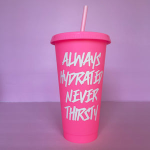 A hot pink plastic cup with a lid and straw that looks like a fast food cup is on a baby pink background. It has "always hydrated never thirsty" in white writing centered down the cup.